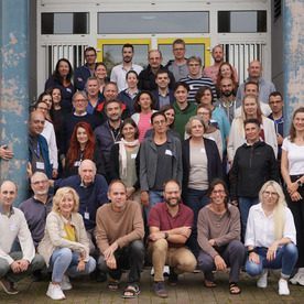 Group photo of around 50 project members, standing together in front of a building.