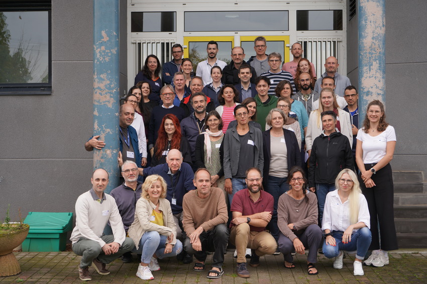 Group photo of around 50 project members, standing together in front of a building.